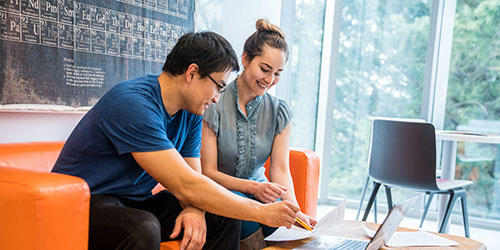 man and woman sitting on a couch looking at paper