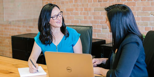 two women sitting at a desk talking